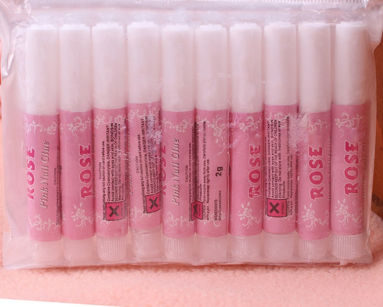 Nail glue tubes in pink packaging from the brand 6ixDrips, arranged neatly in a transparent plastic container.