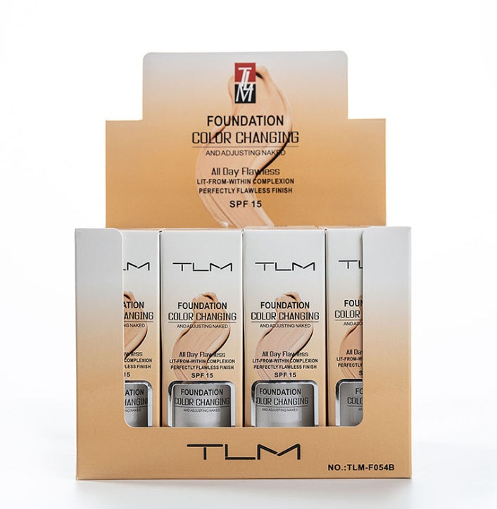 Neutral-toned makeup products displayed in a cardboard stand, including temperature liquid foundation and concealer bottles in various shades. The product is branded as "TLM" and promises color-changing and adjusting capabilities. The image showcases the makeup line's portable and natural-looking foundation and concealer offerings.