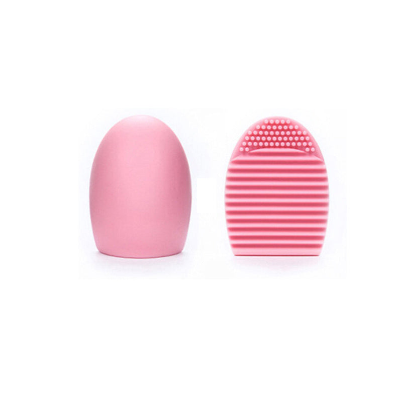 Silicone makeup brush cleaning egg and disc, pink in color, for cleaning and maintaining makeup brushes in a beauty or cosmetics routine.