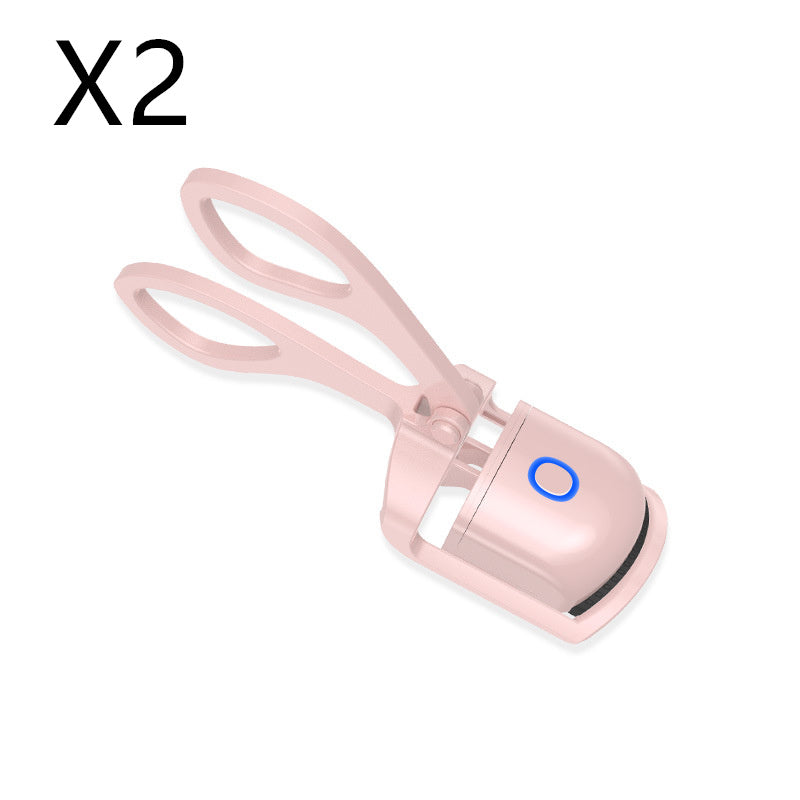 Compact electric heated eyelash curler with temperature control, pink rounded body, and rabbit ear-shaped curling tips for easy, precise lash shaping.