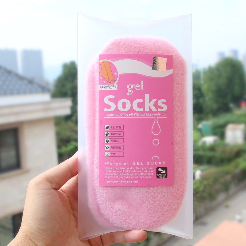 Spa gel socks for moisturizing and exfoliating hands and feet with olive oil and vitamin E, enclosed in a pink fuzzy package.