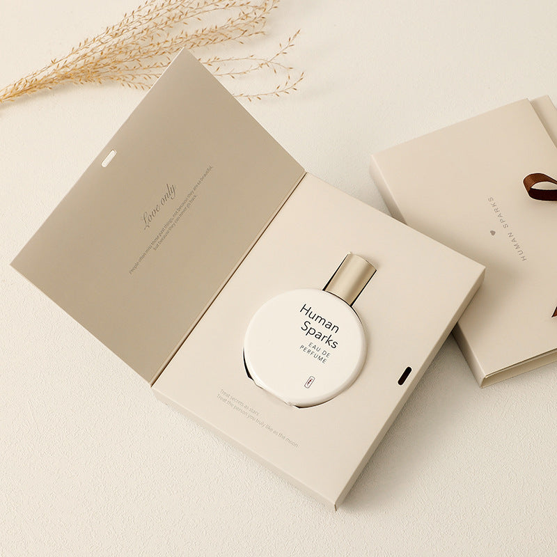 Elegant perfume bottle placed in a white background with natural elements like a dried flower stem, showcasing the refined and minimalist design of the "Human Story" perfume product.